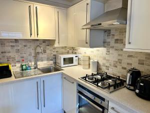 a kitchen with white cabinets and a stove and a microwave at Russell Square Beautiful Quality Apartment in London