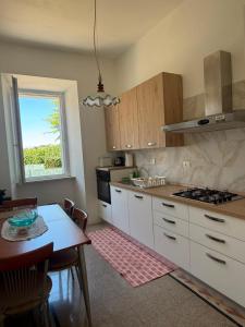 a kitchen with white cabinets and a table and a window at Eden casa vacanze in Morlupo