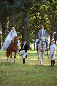 a bride and groom riding on horses in a field at Jumpravmuižas pirtiņa ar kublu in Mežotne