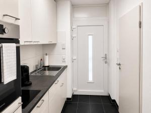 a white kitchen with a sink and a door at Schängel Chic 16 in Koblenz