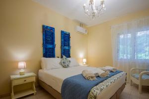 a bedroom with a bed with blue shutters and a chandelier at Paxos Santa Marina Villas in Gaios +103 photos