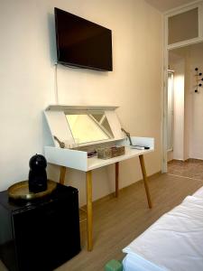 a room with a desk with a tv on a wall at Dimitrovi Guesthouse - Peaceful Stay near Beach with Garden, Sarafovo in Burgas