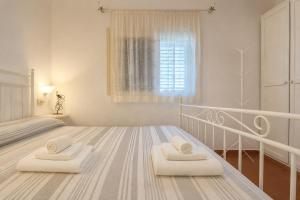 a white bedroom with two white towels on a bed at Carasau 200m from the Beach - Garden - BBQ - Wi-Fi - Parking - Pet Friendly in Budoni