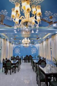 a dining room with tables and chairs and a chandelier at Hotel Cyra palace in Jaipur