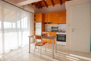 una cucina con mobili arancioni, un tavolo e delle sedie di SkyView Loft a Kalamáta