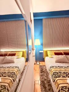 two beds in a room with blue walls at Ama Collection Esclusive Spa Ariosto in Ferrara