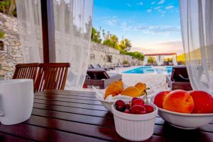 a table with bowls of fruit on a table with a pool at Paxos Santa Marina Villas in Gaios