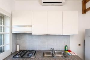 a kitchen with white cabinets and a sink at Carasau 200m from the Beach - Garden - BBQ - Wi-Fi - Parking - Pet Friendly in Budoni +18 photos