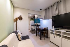 a living room with a couch and a tv and a kitchen at Apartamentos com internet rápida in Maceió