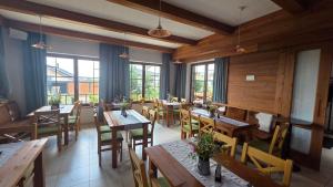 a restaurant with wooden tables and chairs and windows at Vila Araya Mlynica in Mlynica