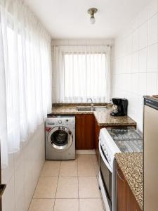 a kitchen with a washing machine and a sink at Hipódromo Sky Penthouse in Cochabamba