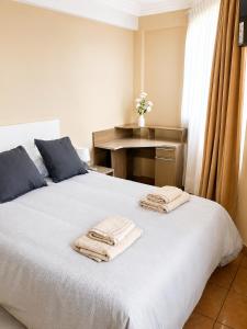 a bedroom with a white bed with towels on it at Hipódromo Sky Penthouse in Cochabamba
