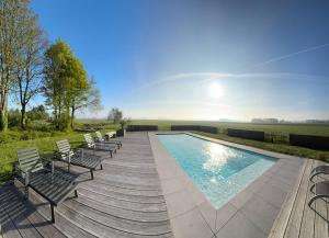 a swimming pool with chairs on a wooden deck at Annense Pracht in Annen