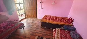a room with two beds in a pink room at Dhankeshwar Dham Homestay in Champawat
