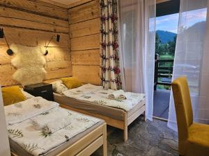 two beds in a room with a balcony at Gościniec Karpacka Dusza in Szczawnica