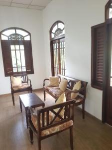 a living room with couches and a table and windows at Calm Cottege in Gampaha