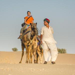 a man and a woman riding a camel in the desert at Yatra Desert Camp & Resort in Jaisalmer