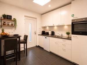 a kitchen with white cabinets and a table with a sink at Schängel Chic 19 in Koblenz