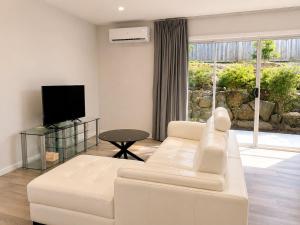 a living room with a white couch and a tv at 18 Pimpama Home in Pimpama