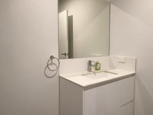 a white bathroom with a sink and a mirror at 18 Pimpama Home in Pimpama +9 photos