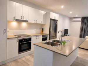 a kitchen with white cabinets and a sink at 18 Pimpama Home in Pimpama