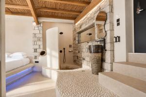 a bedroom with a stone wall with a shower and a bed at Kouros Home & Suites--Faliraki--Adults Only in Faliraki +120 photos
