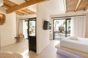 a bedroom with a bed and a tv and a balcony at Kouros Home & Suites--Faliraki--Adults Only in Faliraki
