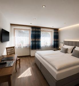 a bedroom with a large bed and a desk at Köcks Bed & Breakfast in Galtür