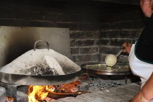 a person cooking food in a pot over a fire at Vatra Traditional Guesthouse in Lekdush
