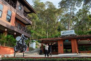 a couple standing in front of a building with a motorcycle statue at Samwise Escapade Hillside Guesthouse - Master Room in Kampong Perlis +2 photos