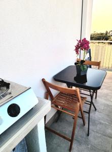 a table and a chair with a vase of flowers on it at Suite Ekaterina Sunsets 2 minuti dal mare in Brolo