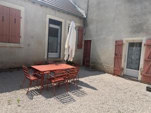 a table with chairs and an umbrella next to a building at chez Marie et Xav in Frasne-les-Meulières