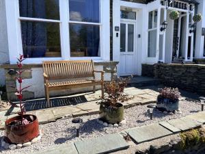 a bench sitting outside of a house with potted plants at Birch Tree House in Windermere