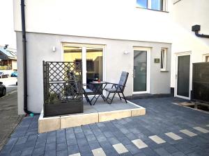 a patio with two chairs and a table in front of a building at Livesto Apartments im Zentrum Bad Driburgs - Modern, Parkplatz, Terrasse, Switch, SmartTV für Familien und B2B in Bad Driburg