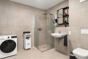 a bathroom with a shower and a sink and a washing machine at Livesto Apartments im Zentrum Bad Driburgs - Modern, Parkplatz, Terrasse, Switch, SmartTV für Familien und B2B in Bad Driburg +21 photos