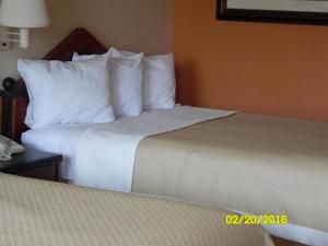 a hotel room with two beds with white pillows at Rodeway Inn & Suites Greensboro Southeast in Greensboro