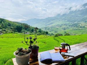 a table with a book and a glass of wine on a table with a field at Peaceful Happiness Bungalow with Valley Views in Sapa