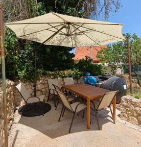 a wooden table and chairs under an umbrella at Aria home in Tsoukalades