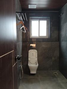 a small bathroom with a toilet and a window at Gamagashree Hotel and Fine Dine in Sāgar +15 photos