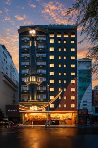 a tall building with a sign on top of it at KiN Hotel Ly Tu Trong Edition in Ho Chi Minh City