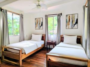 two beds in a room with two windows at Alma Vida Hotel in Manuel Antonio