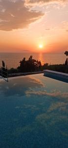 Ein Swimmingpool mit dem Sonnenuntergang im Hintergrund in der Unterkunft Mani Sol Apartments in Kotrónion