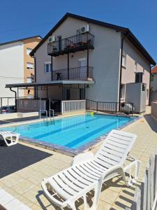 a swimming pool with two lounge chairs and a house at Apartmani Medojević in Radanovići
