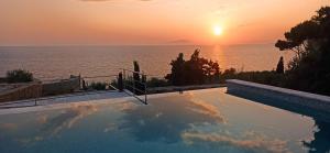 ein Pool mit Blick auf den Ozean bei Sonnenuntergang in der Unterkunft Mani Sol Apartments in Kotrónion