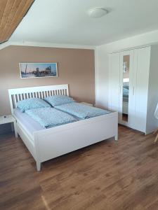 a bedroom with a white bed and a wooden floor at FeWo Waschbär in Waldeck