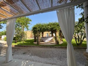 an open patio with white curtains in a yard at Treviè Suite - Torre San Giovanni in Fontanelle