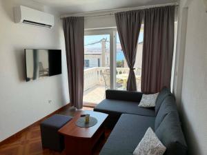 a living room with a blue couch and a large window at Guest House Keskic in Karlobag