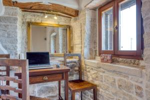 a desk with a laptop on it in a stone room at Holiday House Ante in Žminj