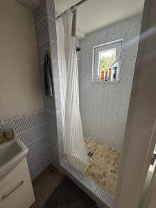 a shower with a white shower curtain in a bathroom at Domek se zahrádkou in Zbečno