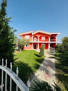 a red house with a fence in front of it at Restorant Hotel Niku in Draç